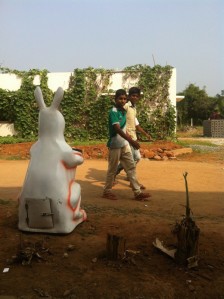 Students walk to school past a giant rabbit waste bin
